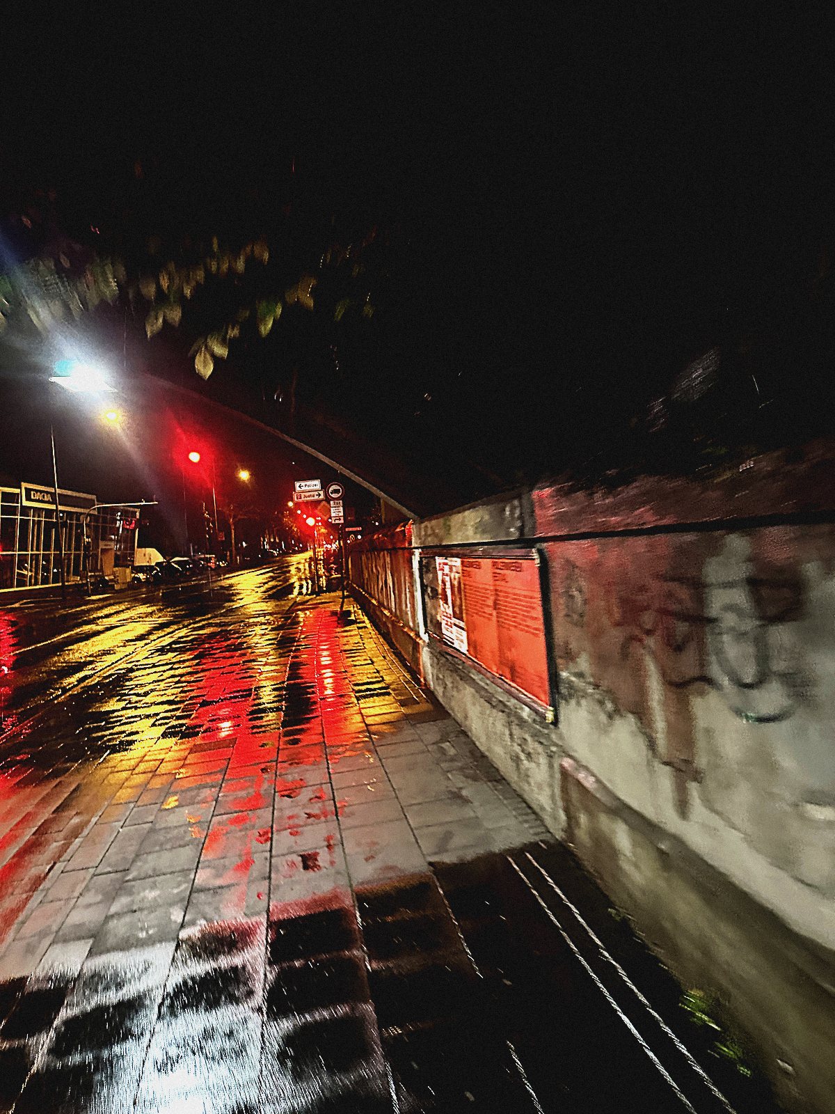 Rot gespiegelte regennasse Gasse bei Nacht