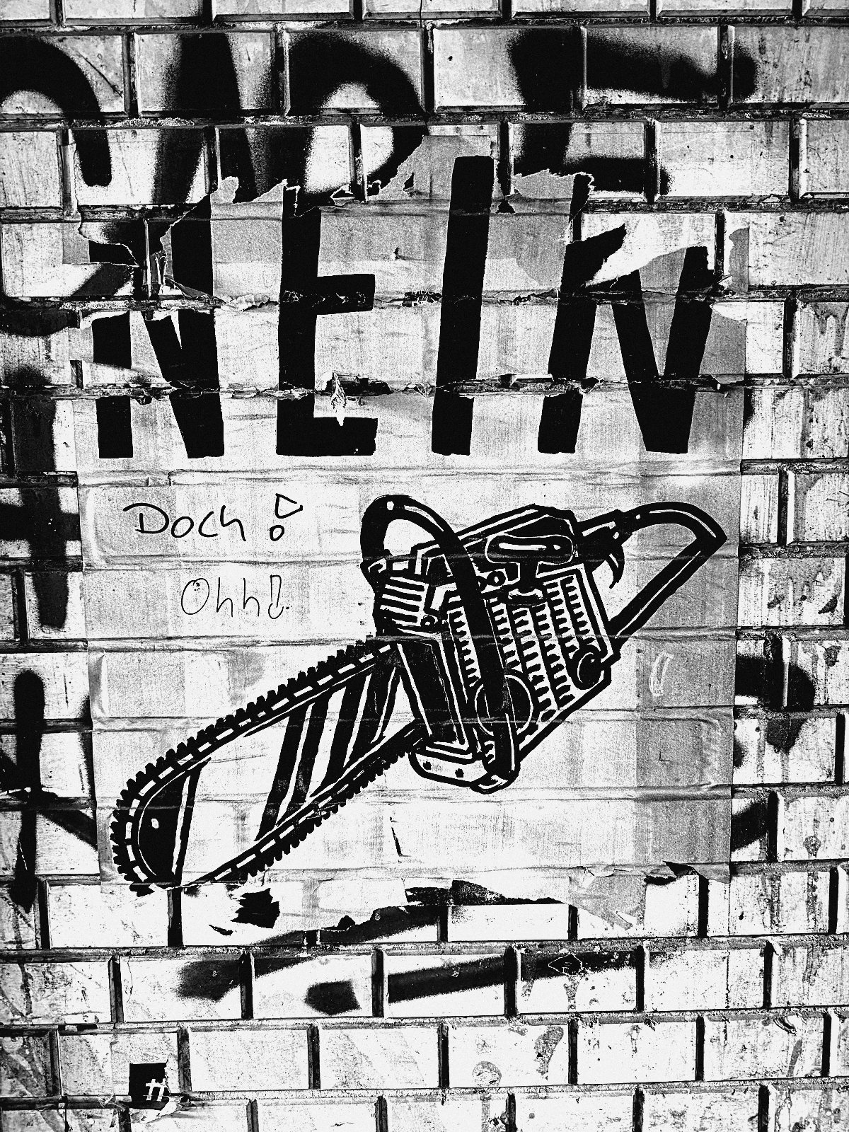 Wheatpaste mit Schriftzug Nein und Kettensäge auf Klinkerwand