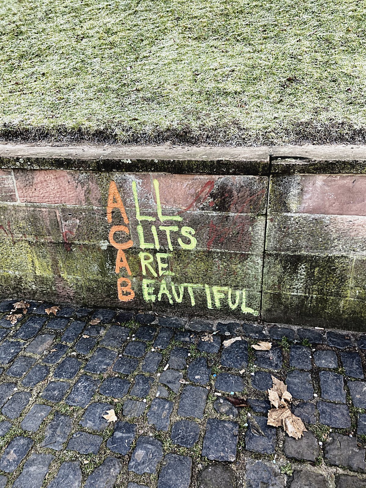 All Clits Are Beautiful in bunter Kreide auf eine Bahnsteigkante geschrieben