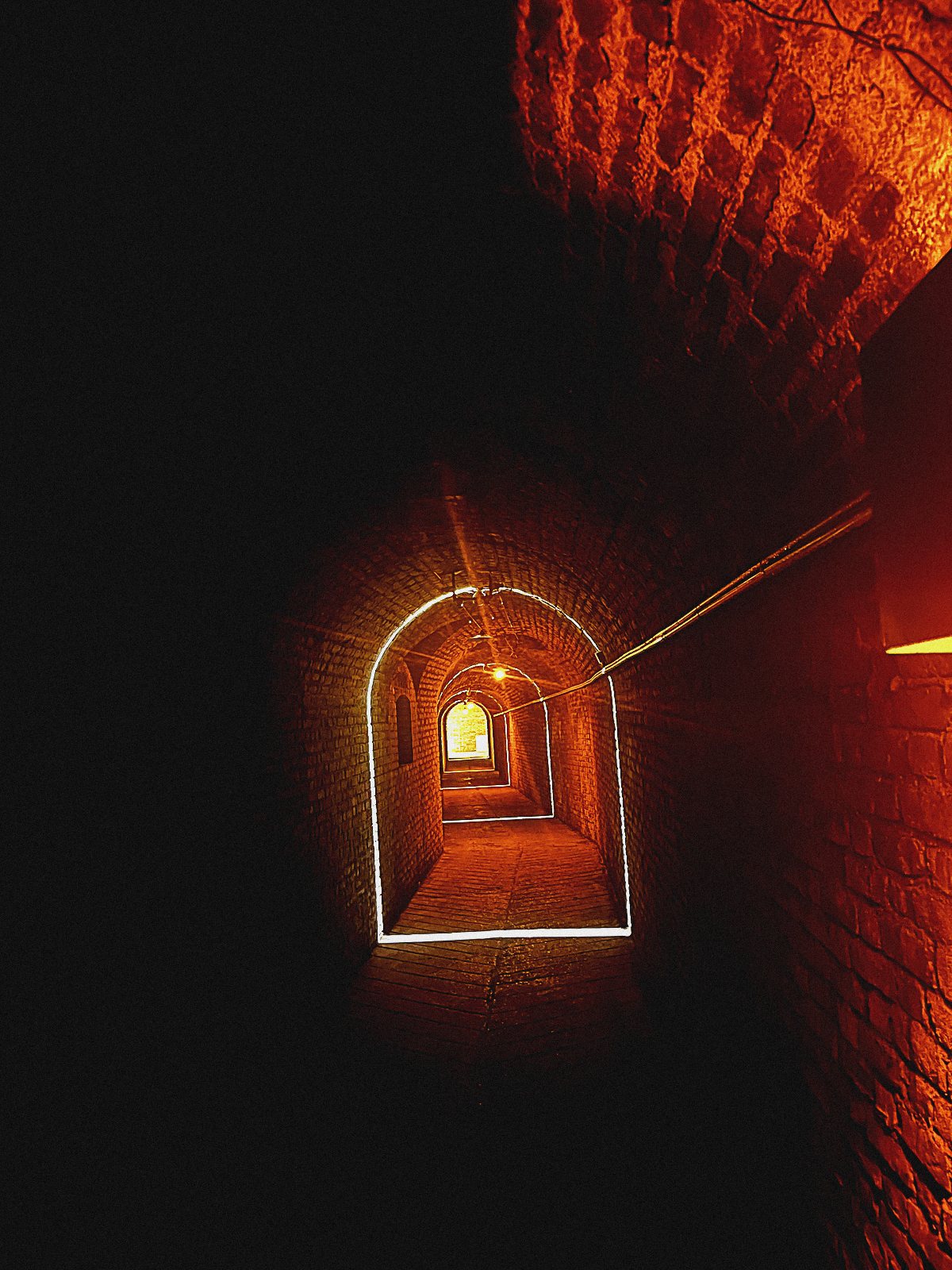 Roter Backsteintunnel mit leuchtender Tür am Ende