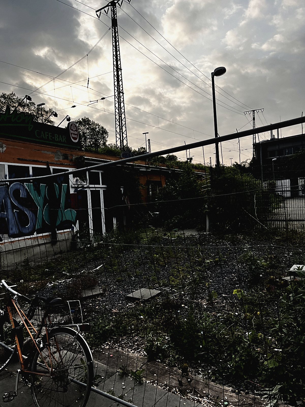 Überwuchertes verlassenes Kioskhäuschen mit Graffiti am Bahndamm